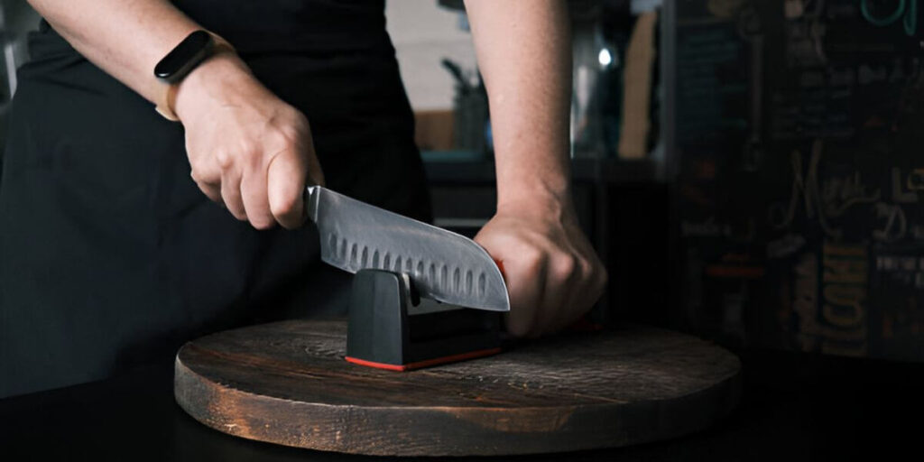 A person uses a chef's choice knife sharpener
