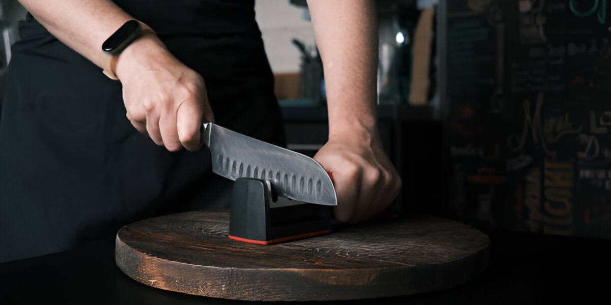 A person uses a chef's choice knife sharpener