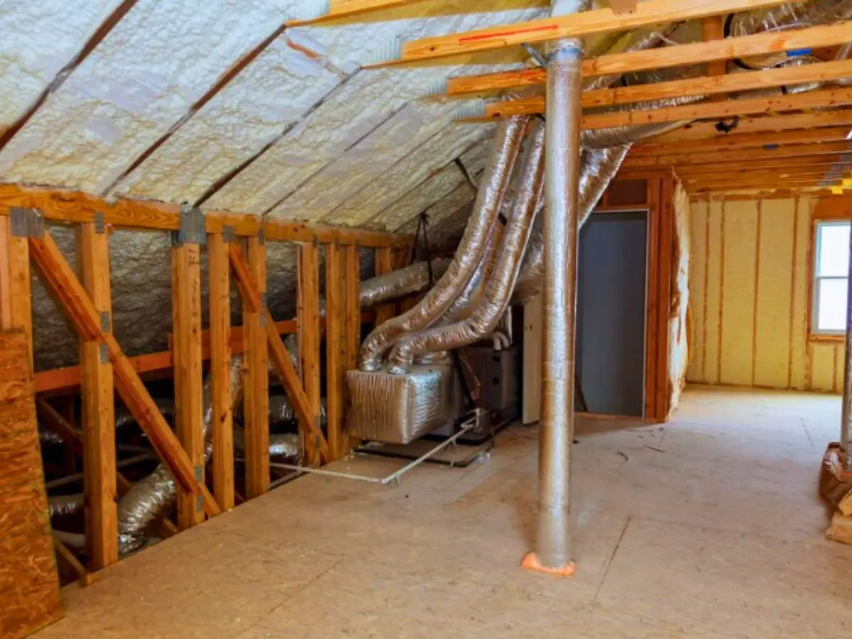 Ductwork and air vents running through a wooden-framed attic space with insulation